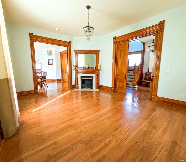 unfurnished living room with an inviting chandelier and hardwood / wood-style floors