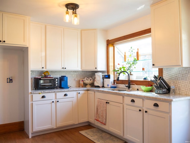 kitchen featuring white cabinetry, sink, light hardwood / wood-style flooring, and light stone counters