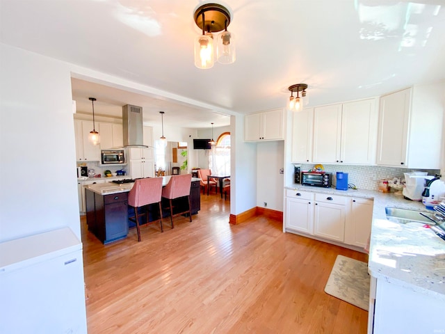 kitchen with white cabinets, island exhaust hood, stainless steel microwave, and pendant lighting