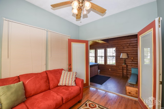 living room featuring ceiling fan, hardwood / wood-style flooring, and rustic walls