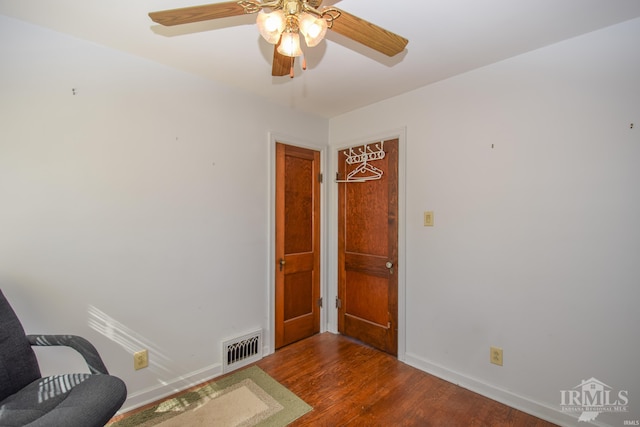 living area featuring ceiling fan and dark hardwood / wood-style floors