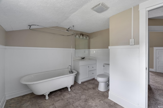 bathroom with a textured ceiling, a washtub, vaulted ceiling, vanity, and toilet