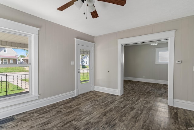 foyer entrance with wooden walls, ceiling fan, and dark wood-type flooring