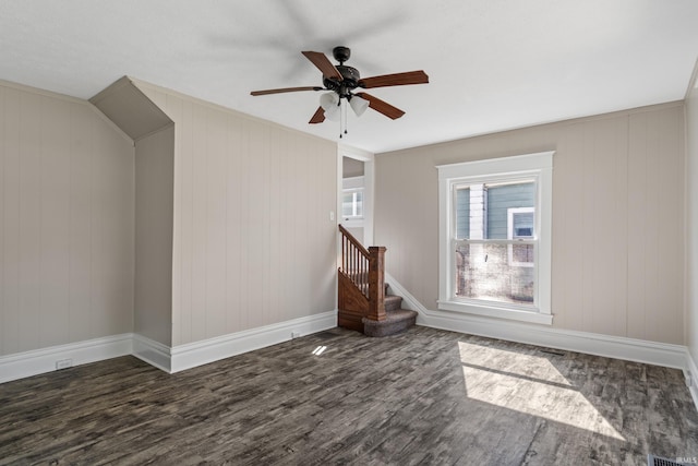 additional living space with ceiling fan, wood walls, and dark wood-type flooring