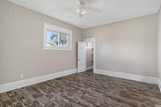 unfurnished bedroom with wooden walls, ceiling fan, and dark hardwood / wood-style floors