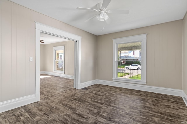 empty room featuring ceiling fan, wood walls, and dark hardwood / wood-style flooring