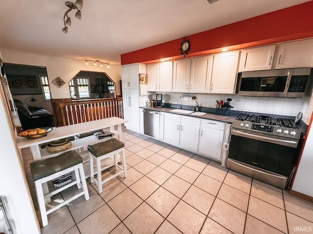 kitchen with tasteful backsplash, sink, white cabinetry, stainless steel appliances, and light tile patterned floors