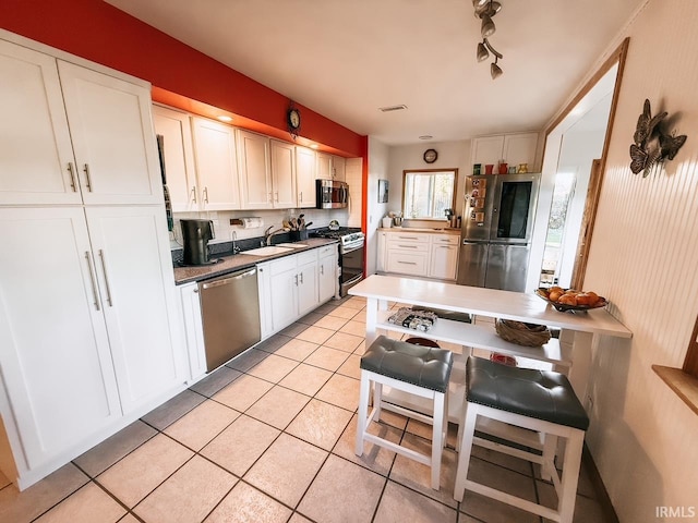 kitchen with white cabinets, stainless steel appliances, and light tile patterned floors