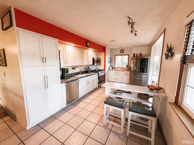 kitchen with stainless steel appliances, white cabinets, and light tile patterned floors