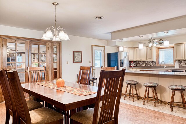 dining area featuring light wood-type flooring, sink, and an inviting chandelier