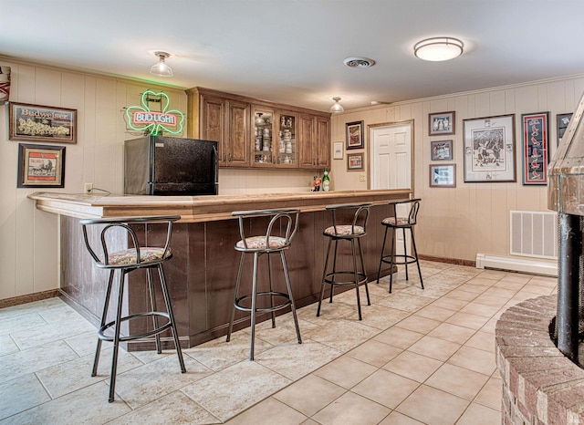 bar featuring wooden walls, black fridge, and a baseboard radiator