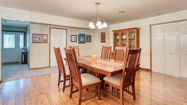 dining area with light hardwood / wood-style floors and a chandelier