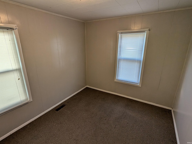 empty room featuring dark colored carpet and crown molding