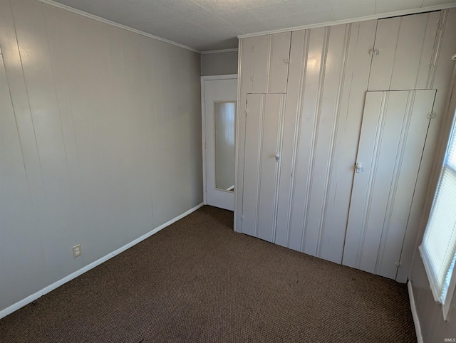 unfurnished bedroom featuring ornamental molding, a closet, and dark colored carpet