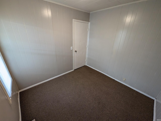 unfurnished room featuring carpet floors, wood walls, and ornamental molding