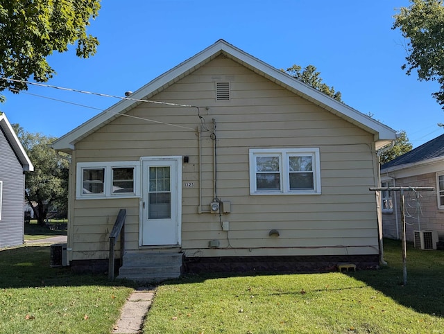 rear view of property featuring a lawn and central AC unit