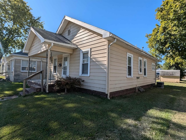 view of front of house featuring a storage shed, central air condition unit, and a front yard