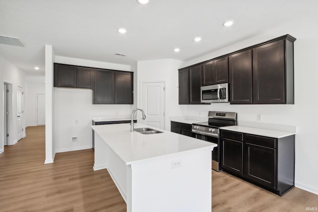 kitchen featuring appliances with stainless steel finishes, light hardwood / wood-style flooring, a kitchen island with sink, and sink