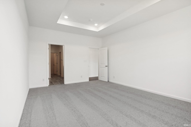 carpeted spare room with a tray ceiling