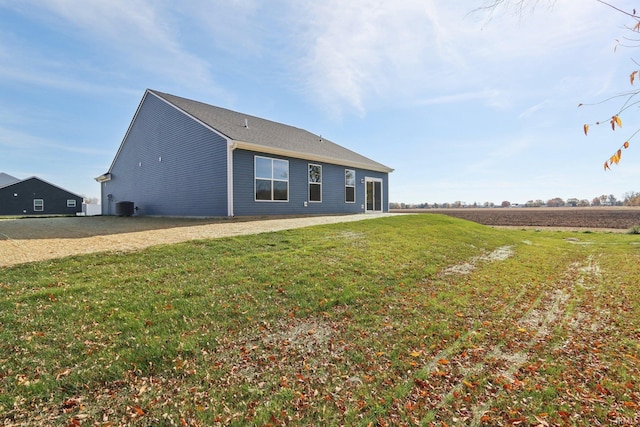 back of property featuring central AC and a yard