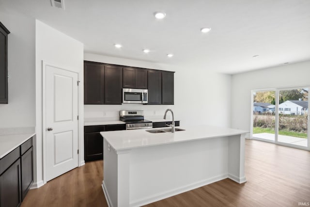 kitchen with dark hardwood / wood-style flooring, dark brown cabinetry, stainless steel appliances, sink, and an island with sink