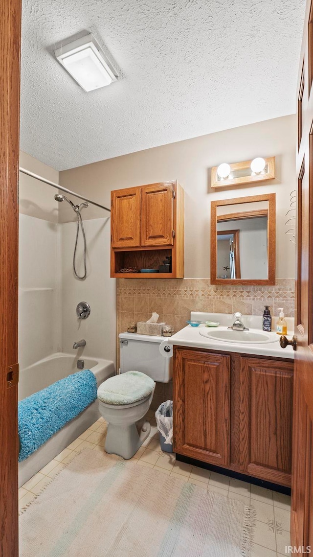 full bathroom featuring a textured ceiling, bathing tub / shower combination, vanity, and toilet