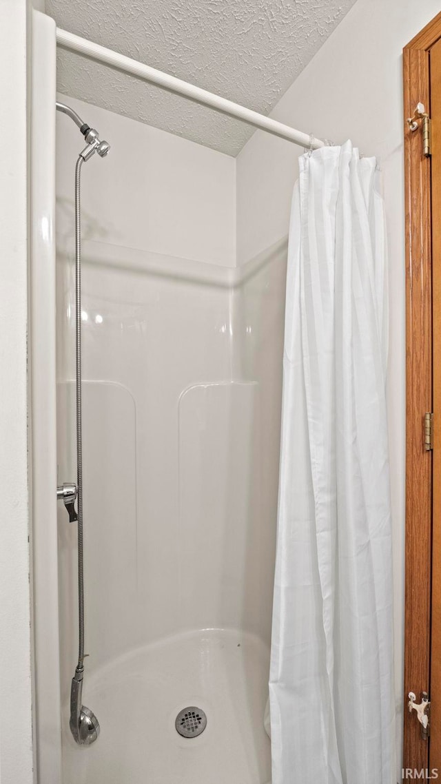 bathroom featuring a shower with curtain and a textured ceiling