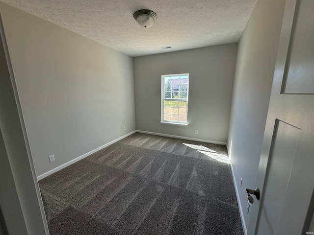 unfurnished room featuring a textured ceiling and dark colored carpet