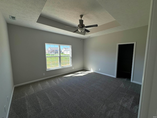 carpeted spare room featuring a textured ceiling, a tray ceiling, and ceiling fan