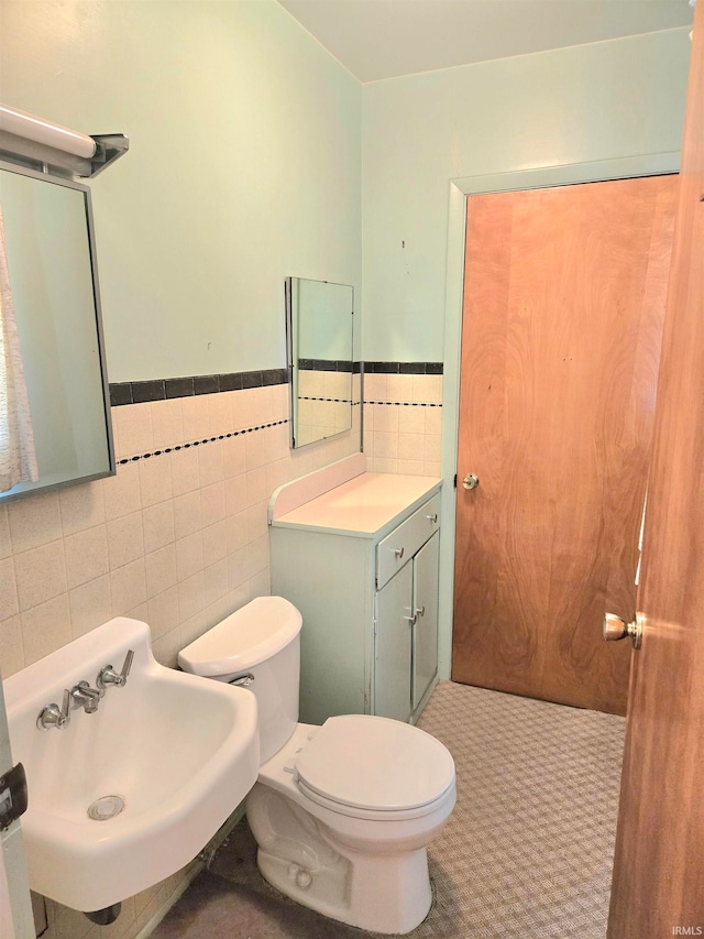 bathroom featuring tile walls, vanity, and toilet