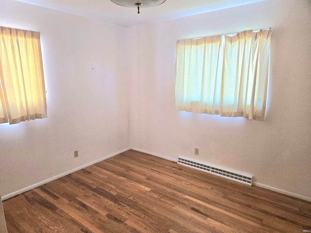 unfurnished room featuring a baseboard heating unit and hardwood / wood-style flooring