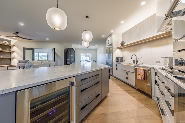 kitchen featuring beverage cooler, appliances with stainless steel finishes, plenty of natural light, and decorative light fixtures