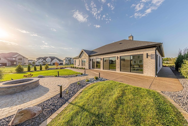 back of house with a lawn, a fire pit, and a patio area