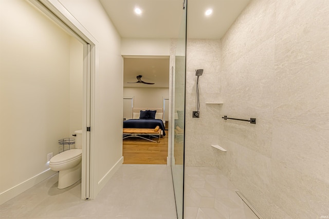 bathroom featuring wood-type flooring, tiled shower, and toilet