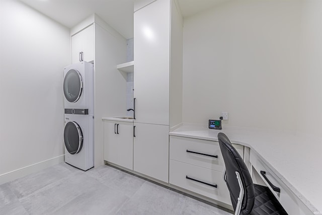 laundry area with cabinets, stacked washer / dryer, and sink