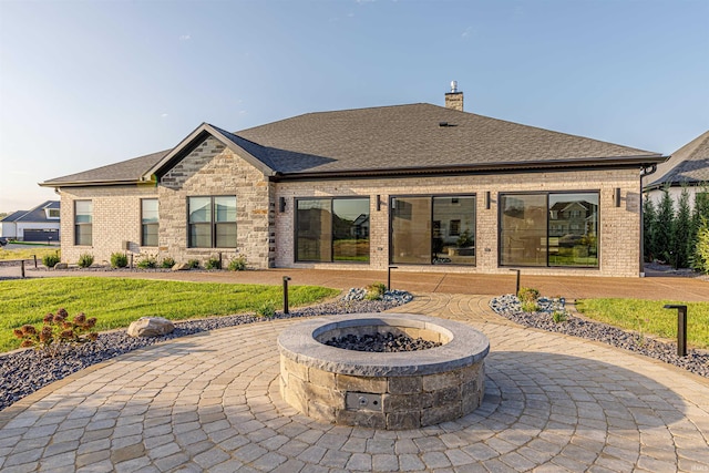 rear view of property with a lawn, a patio area, and a fire pit