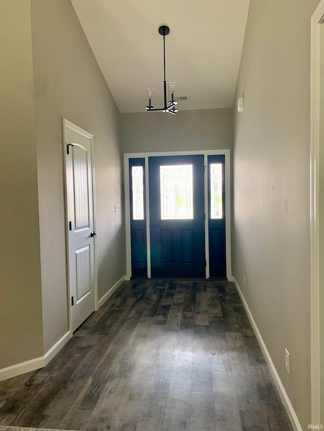 entryway with a notable chandelier, vaulted ceiling, and dark hardwood / wood-style floors