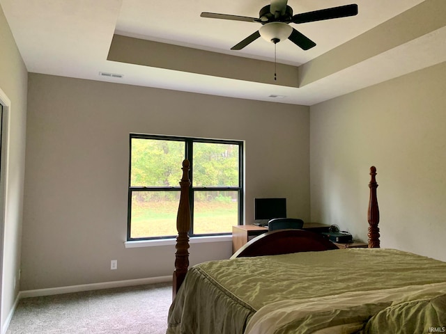 bedroom with a tray ceiling, ceiling fan, and carpet flooring