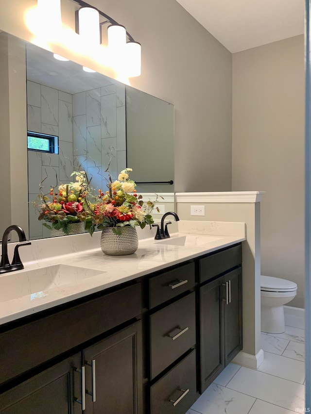 bathroom with a tile shower, vanity, and toilet