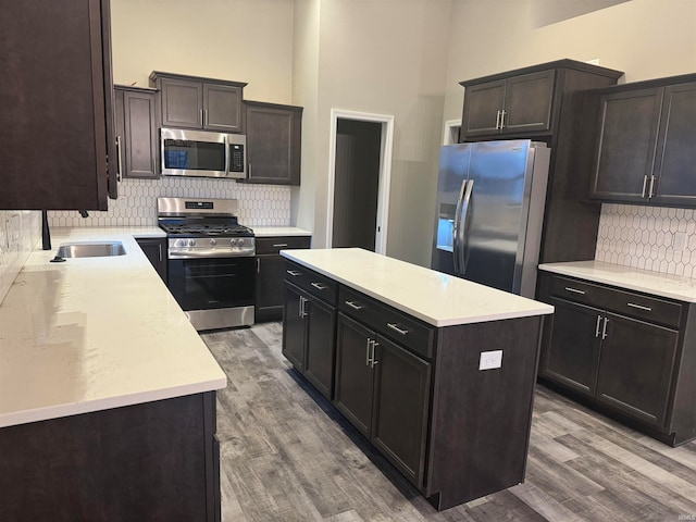 kitchen with appliances with stainless steel finishes, hardwood / wood-style floors, decorative backsplash, and a kitchen island