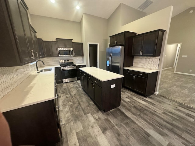 kitchen featuring a center island, carpet flooring, sink, high vaulted ceiling, and appliances with stainless steel finishes