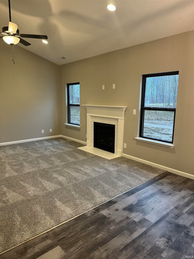 unfurnished living room with ceiling fan, plenty of natural light, and dark carpet