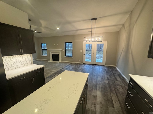 kitchen with decorative backsplash, ceiling fan with notable chandelier, dark hardwood / wood-style floors, and decorative light fixtures