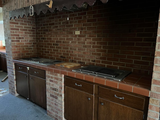 kitchen with light carpet, dark brown cabinets, and tile countertops