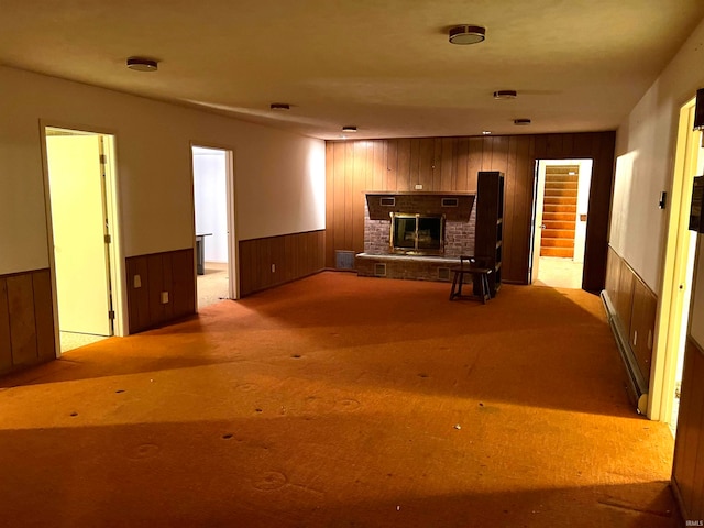 unfurnished living room with light colored carpet, wooden walls, and a fireplace