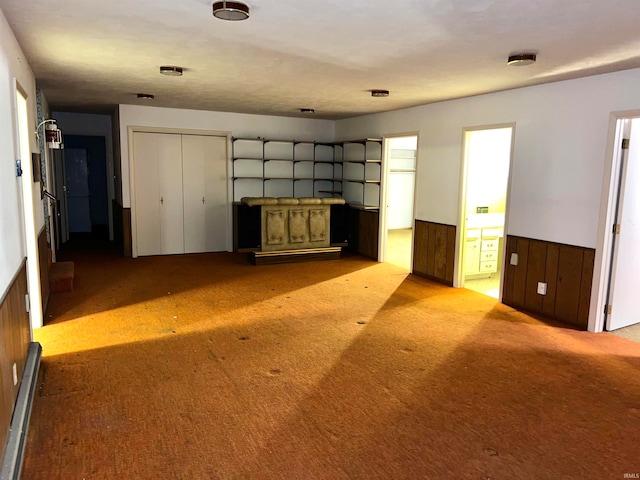 unfurnished living room featuring wooden walls and light colored carpet