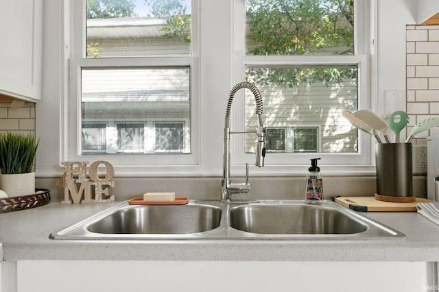 interior details featuring sink, white cabinets, and tasteful backsplash