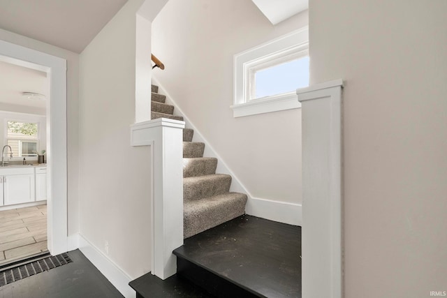 stairway featuring wood-type flooring and sink