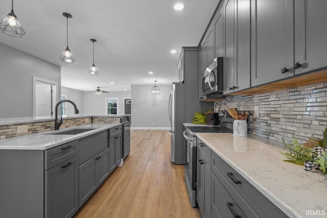 kitchen with appliances with stainless steel finishes, gray cabinetry, pendant lighting, and sink