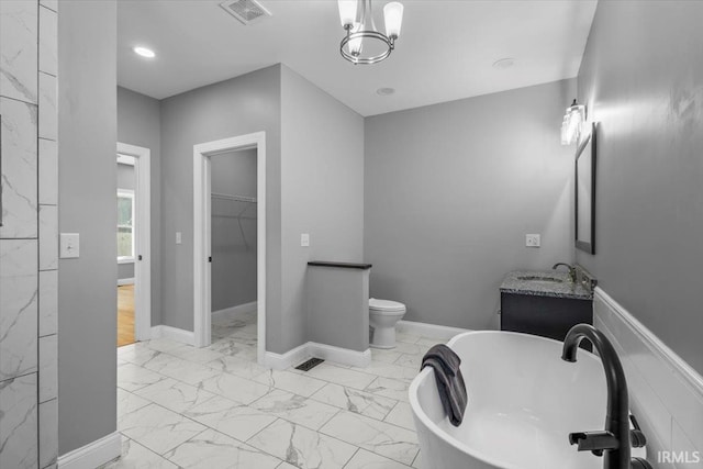 bathroom with a notable chandelier, a tub, toilet, and vanity